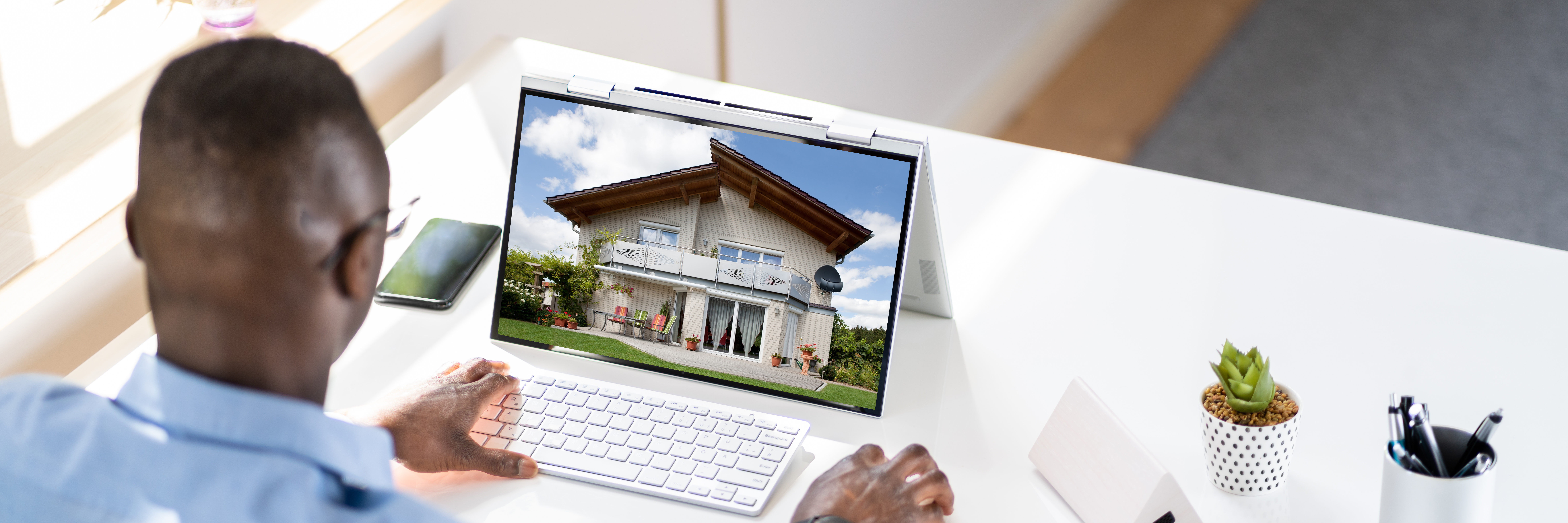 Man Selecting New House On Laptop At Home